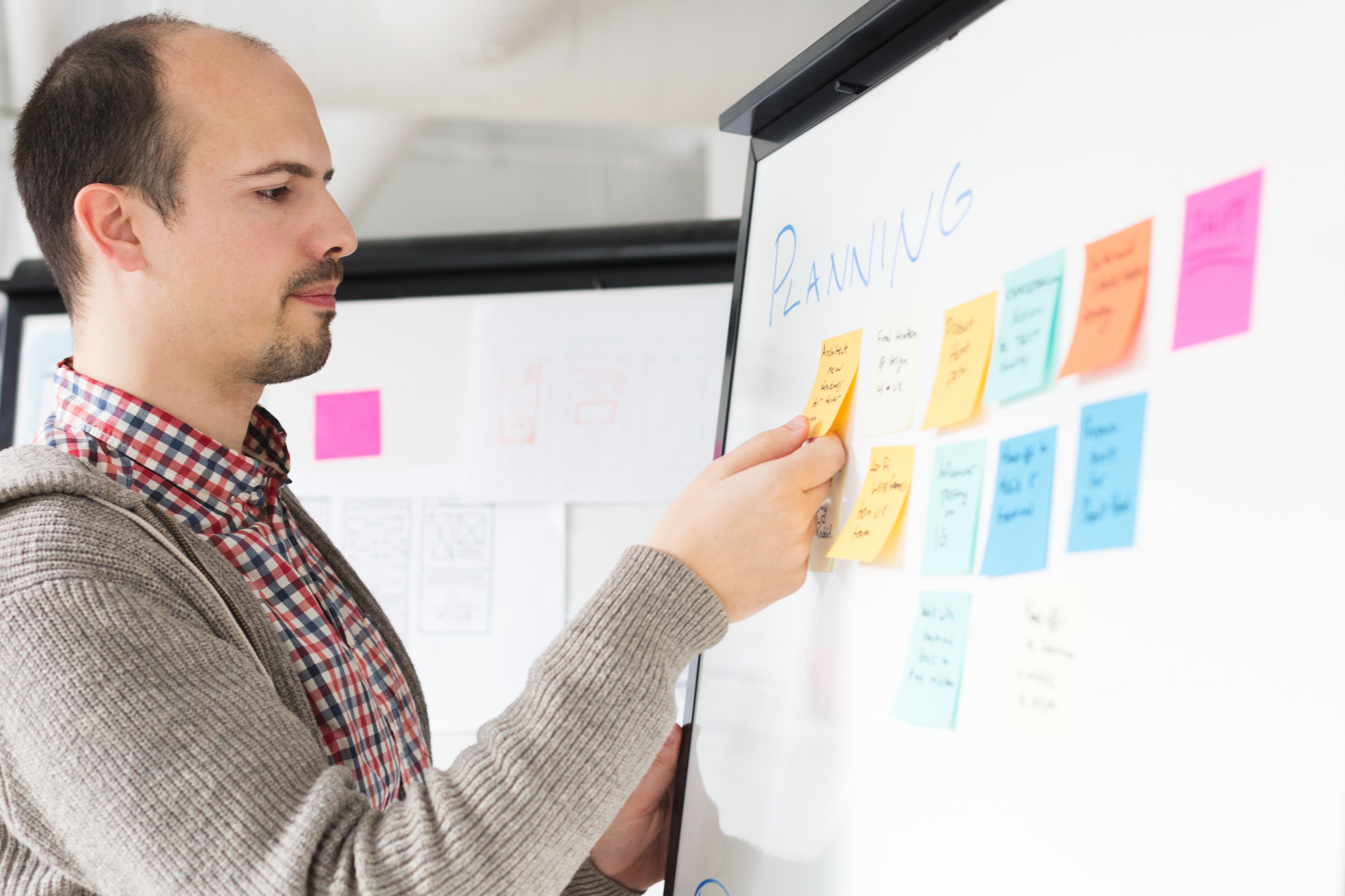 Planning: man organizing ideas on a whiteboard with sticky notes